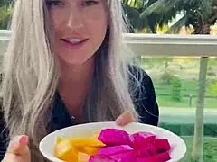 An eye catching model presenting chopsticks and exotic fruits in erotic costume
